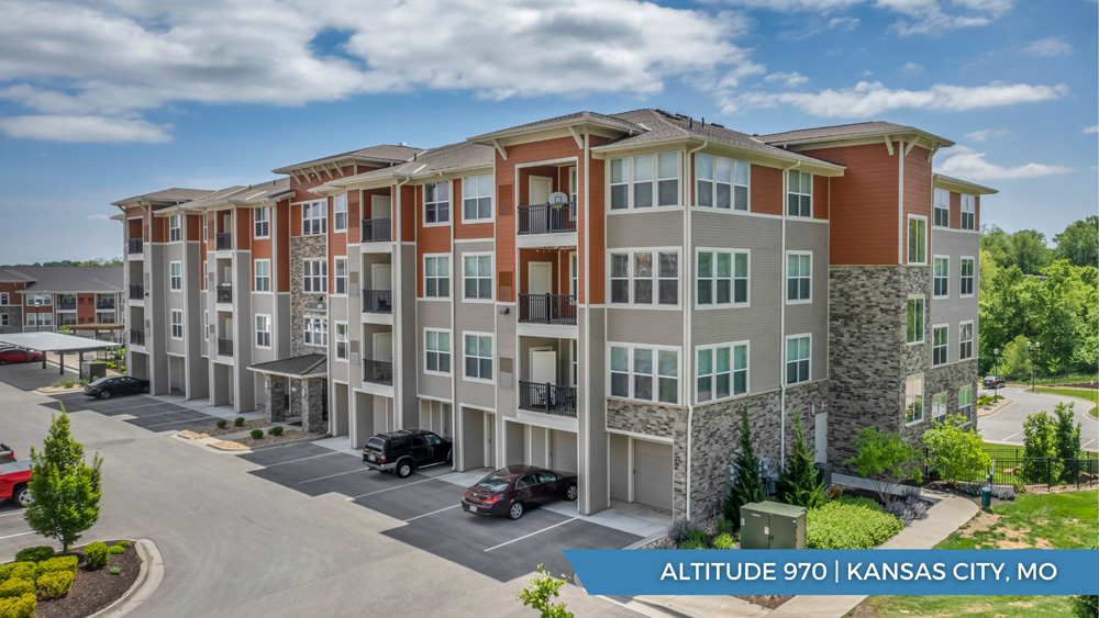 A modern four-story apartment building with stone and wood accents, large windows, balconies, and parked cars outside. Lush greenery surrounds the property. Text reads: Altitude 970 | Kansas City, MO.