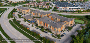 Aerial view of a large apartment complex with multiple buildings, surrounded by parking lots, greenery, and nearby roads in West Des Moines, Iowa. The property is labeled as Watermark at Jordan Creek.