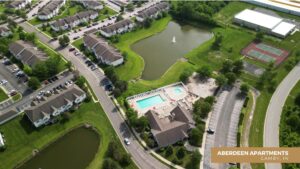 Aerial view of Aberdeen Apartments in Camby, IN, showing residential buildings, a swimming pool, a pond with a fountain, tennis courts, parking lots, and green spaces.