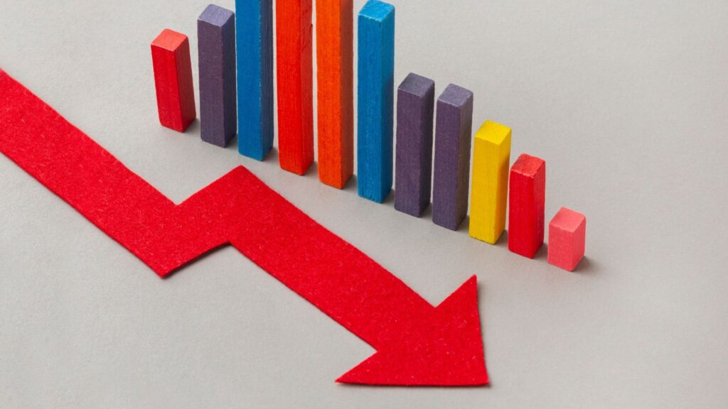 A red downward arrow in front of multicolored bar graphs, representing a decline or decrease in statistics or performance.