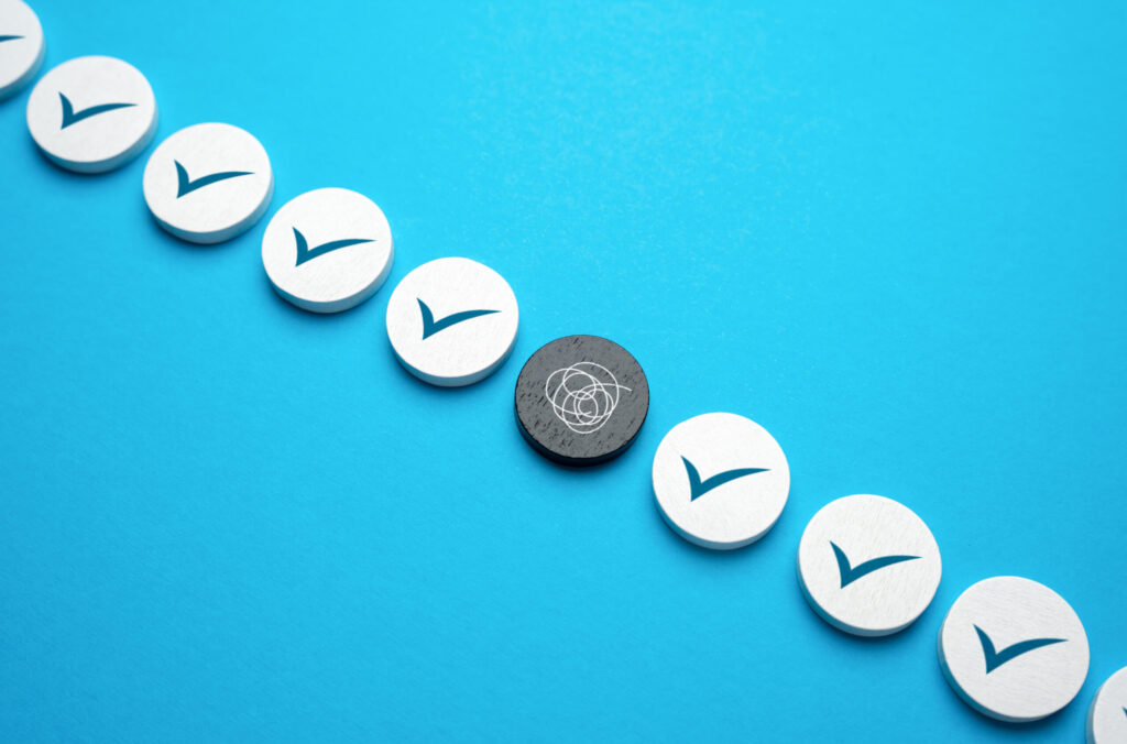 A row of white circular tokens with blue checkmarks is arranged diagonally on a blue background, with one black token featuring a tangled scribble symbol among them.