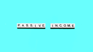 White letter tiles spell PASSIVE INCOME on a bright blue background, with the two words separated by a small gap.