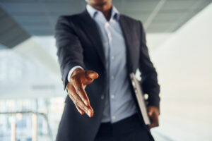 Successful agreement. Young African American businessman in black suit is indoors.