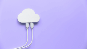 A white cloud-shaped cutout with three white cables plugged into it, set against a light purple background, symbolizing cloud computing or data connectivity.