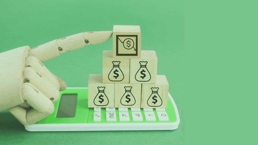 A wooden robotic hand points at wooden blocks stacked on a green calculator. The blocks display money bag icons and a chart with a dollar sign, symbolizing finance and technology. The background is solid green.