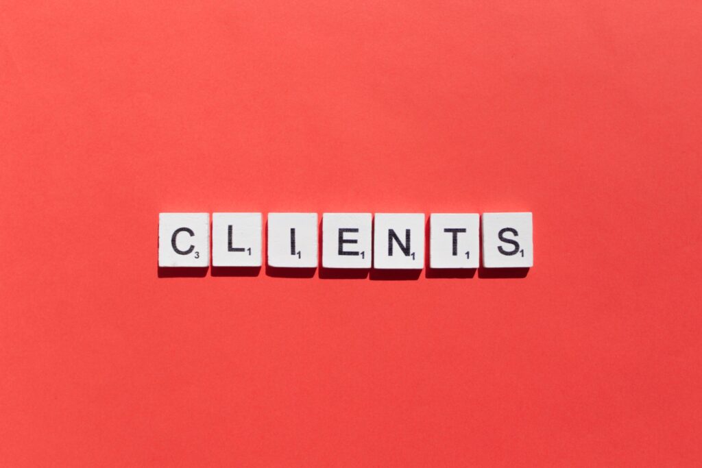 Scrabble tiles spelling out CLIENTS are arranged in a row on a bright red background.