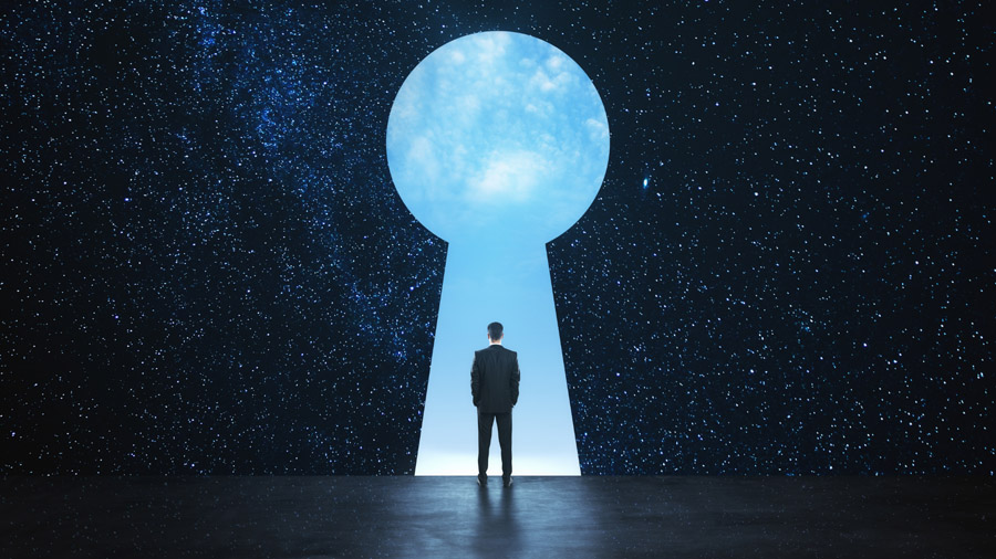 A person in a suit stands in front of a giant keyhole-shaped portal, surrounded by a star-filled night sky, gazing into a bright, cloudy light beyond the opening.